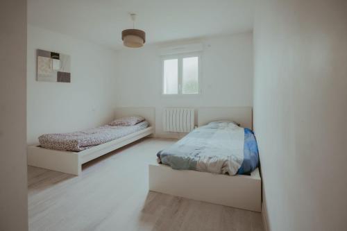 a white bedroom with two beds and a window at pepiniere in Nogent-sur-Seine