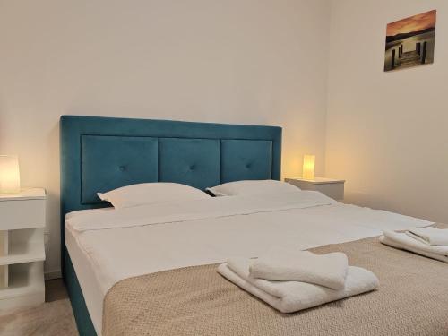 a large bed with a blue headboard and white sheets at Mare et Silva Apartment Dubrovnik in Dubrovnik