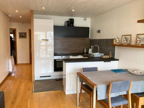 una cucina con tavolo da pranzo e una cucina con banconi neri di Evasion Sérénité à Chamonix Mont-Blanc a Chamonix-Mont-Blanc