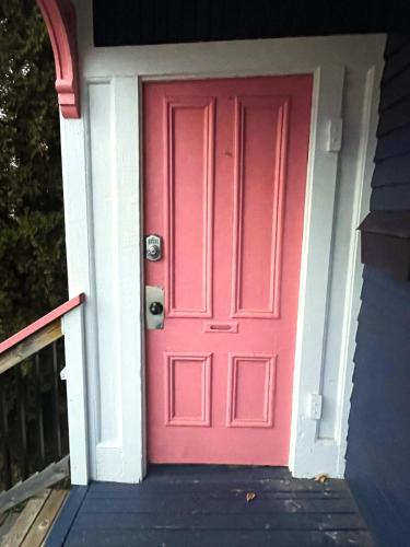 a pink door on a house with a porch at Dominion Place Studio in Moncton
