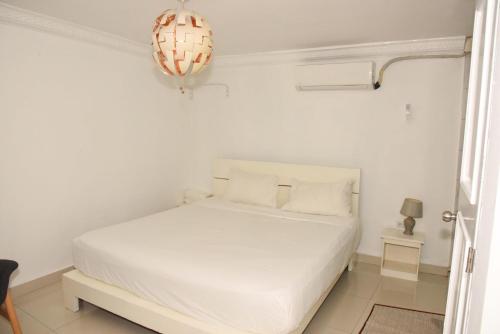 a white bedroom with a white bed and a chandelier at Hostel Gato Colonial in Santo Domingo