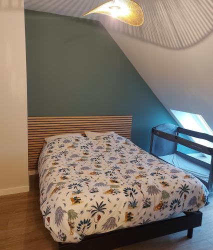 a bedroom with a bed with a comforter on it at Au Clair De Lune in Pléneuf-Val-André