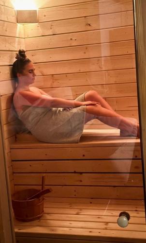 a woman is sitting in a sauna at BUKOWA Jezioro Żywieckie Beskid Żywiecki Śląski Sauna Jacuzzi Kominek Morsowanie Tresna Żywiec Szczyrk in Tresna