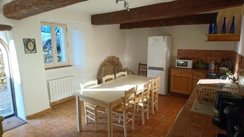 une cuisine avec une table et des chaises dans une pièce dans l'établissement Grande maison de village - solarium et terrasse, à Saint-Martin-de-Castillon
