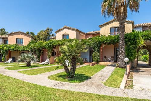 a large house with palm trees and a sidewalk at Classical Res Baia Delle Palme Prem Bilo 4 person in Santa Margherita di Pula