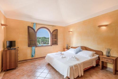 a bedroom with a large white bed with a window at Classical Res Baia Delle Palme Prem Bilo 4 person in Santa Margherita di Pula