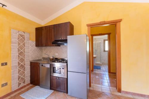 a kitchen with a white refrigerator and wooden cabinets at Classical Res Baia Delle Palme Prem Bilo 4 person in Santa Margherita di Pula