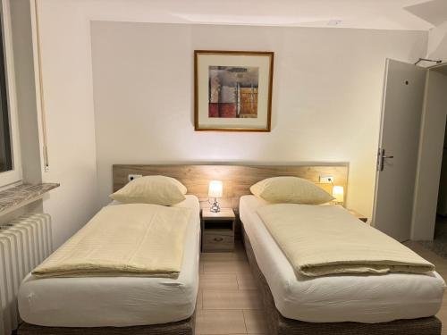 two beds in a room with a table and a picture at Hotel Soad in Salach