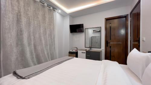 a bedroom with a white bed and a television at Pyramids Tower view inn in Nazlat as Sammān