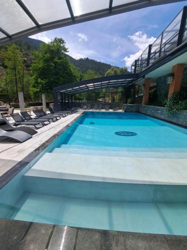 une piscine avec des chaises et un bâtiment dans l'établissement Les Jardins De La Glacière, à Corte