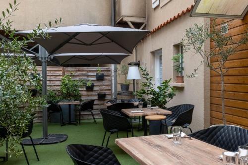 un patio avec tables, chaises et un parasol dans l'établissement Logis Hôtel Restaurant La Châtellenie, à Availles-Limouzine