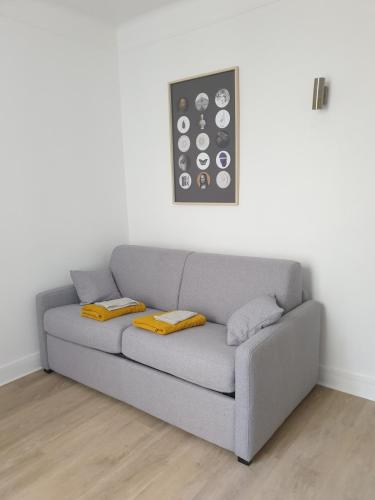 a gray couch in a living room with two pillows at Double-studio 4p Calme 100m métro idéal Séjour Maison examens in Cachan