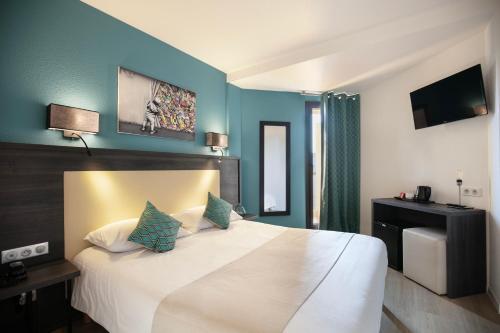 a bedroom with a large white bed with blue walls at Hôtel Le Collier in Antibes