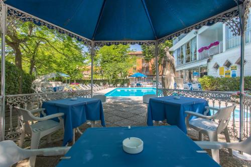 a patio with blue tables and chairs and a pool at Hotel Gioiello in Cesenatico