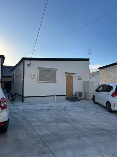 a white building with two cars parked in a parking lot at OUCHI Oaramachi - Vacation STAY 18642 in Goto