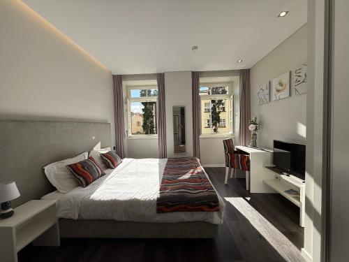 une chambre avec un lit, un bureau et une télévision dans l'établissement Gold Center Funchal 103, à Funchal