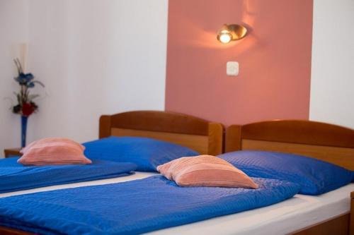two beds with blue sheets and pink pillows on them at Apartments Meri - 1 in Lopar