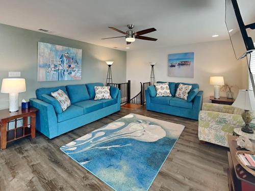a living room with blue couches and a ceiling fan at Frisco- Flats in Rockport