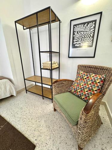 a wicker chair with a pillow and a book shelf at Sands Apartments in St Paul's Bay