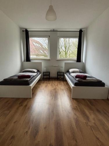 two beds in a room with wooden floors and two windows at Case Five Aparthotel mit Parkplatz in Datteln