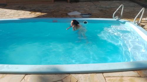 a woman standing in a swimming pool at Chales rota da pedra in São Bento do Sapucaí
