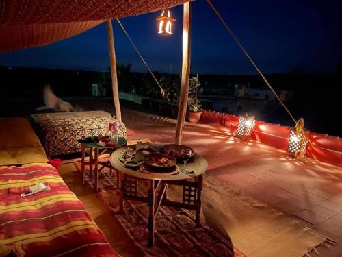 a patio with a table and chairs and lights at Magnifique Chalet en bois collé à la forêt de Benslimane in O Ben Slimane