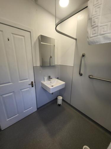 a white bathroom with a sink and a mirror at The Wee House -Coorie Doon Stays in Troon
