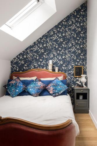 a bedroom with a bed with blue floral wallpaper at LE COTTAGE Gîte de charme au pied du Château in Combourg