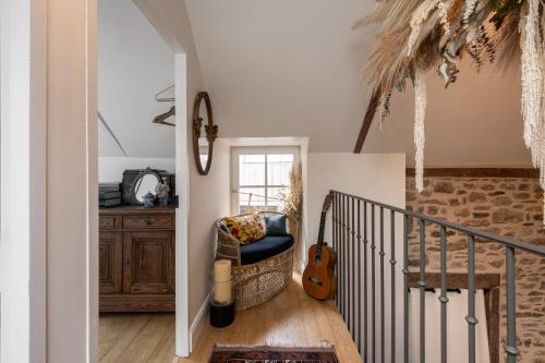 a living room with a chair and a guitar at LE COTTAGE Gîte de charme au pied du Château in Combourg
