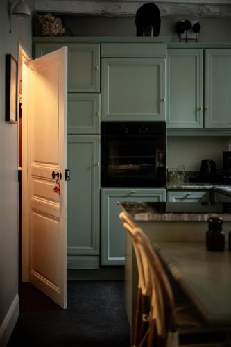 a kitchen with green cabinets and an open door at LE COTTAGE Gîte de charme au pied du Château in Combourg