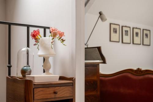 a vase with flowers on a table next to a piano at LE COTTAGE Gîte de charme au pied du Château in Combourg