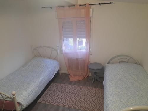 a bedroom with two beds and a window and a table at Family House in Beauvais