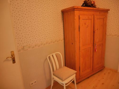 a white chair sitting next to a wooden cabinet at Villa Kükenkamp in Rätzlingen