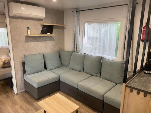 a living room with a couch and a window at Mobile-home 6-8 personnes camping Les viviers in Lège-Cap-Ferret