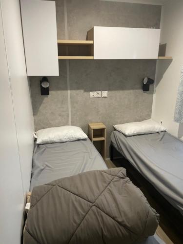 a room with two beds in a room at Mobile-home 6-8 personnes camping Les viviers in Lège-Cap-Ferret