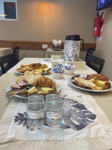 a table with plates of food and glasses of water at Hotel Olavarria in Olavarría