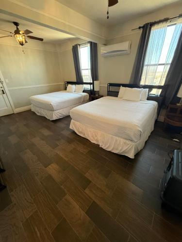 two beds in a hotel room with wooden floors at The Gadsden Hotel in Douglas