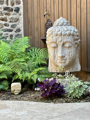 a statue of a head in a garden with flowers at LE COTTAGE Gîte de charme au pied du Château in Combourg