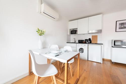 une cuisine blanche avec une table et des chaises blanches dans l'établissement T2 Havre paix coeur Toulouse - St Georges - Climatisation - Wifi - Parking 2min, à Toulouse