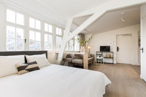 a white bedroom with a large bed and a living room at City Apartments Nijmegen in Nijmegen