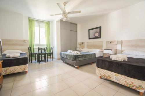 a bedroom with three beds and a table and chairs at Hotel Dos Mundos in Buenos Aires