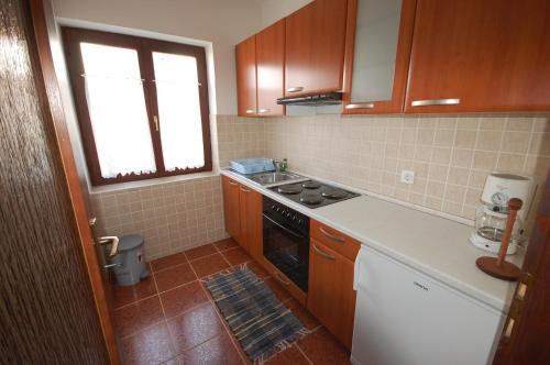 a small kitchen with a stove and a window at Apartment Djuka in Njivice