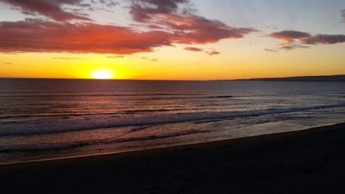 a sunset on a beach with the ocean at La Selva Beach Ocean Front Townhome - Direct Beach & Ocean Access in La Selva Beach
