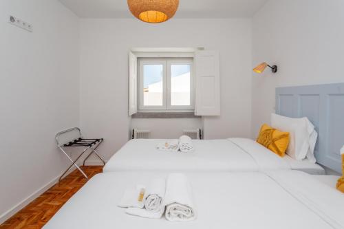 una camera da letto bianca con due letti e una finestra di BeGuest Cascais Blue Family Home a Cascais