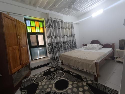 ein Schlafzimmer mit einem Bett und einem Buntglasfenster in der Unterkunft Zanzilife in Zanzibar City