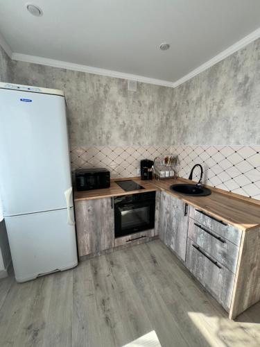 a kitchen with a white refrigerator and a sink at Двухкомнатная квартира в центре Сейфуллина 22 in Balqash
