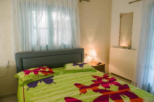 a bedroom with a bed with a green comforter and a window at villa eri in Kalamákion