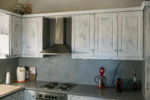 a kitchen with white cabinets and a stove at villa eri in Kalamákion