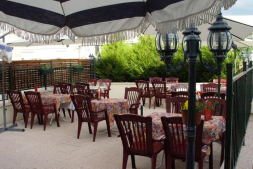 un patio esterno con tavoli, sedie e un ombrellone di Hôtel Le Saint Martin a Bourg-Sainte-Marie