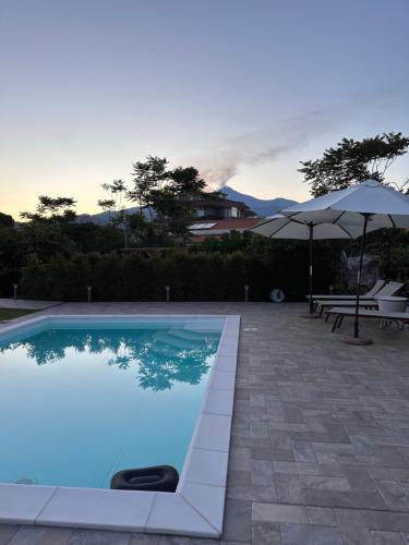 a swimming pool with an umbrella and a table and chairs at La Casetta di Lollò in Aci SantʼAntonio